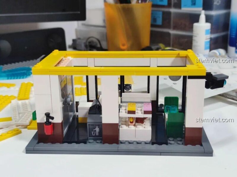 Chi tiết nội thất bên trong Mô hình cửa hàng Shell Select 66027, bao gồm tủ lạnh và kệ hàng.