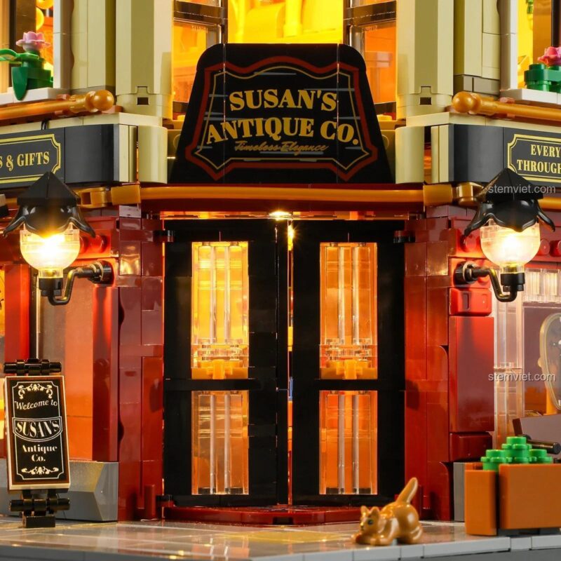 Cận cảnh lối vào chính của bộ xếp hình FunWhole 9033, với biển hiệu Susan's Antique Co., hai chiếc đèn lồng cổ điển và chú mèo tam thể đáng yêu.