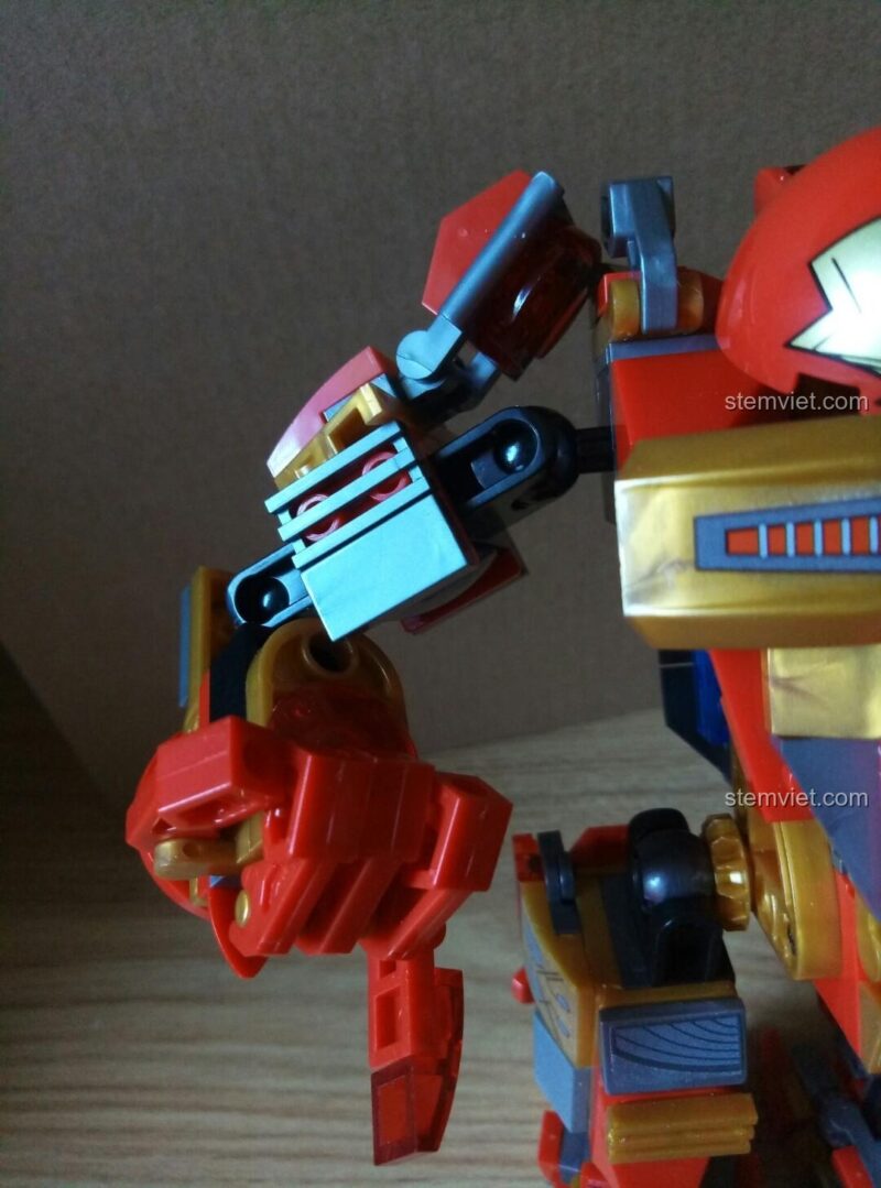 Minifigure Iron Man đang ngồi trên ụ súng, sẵn sàng chiến đấu bên cạnh bộ giáp Hulkbuster.