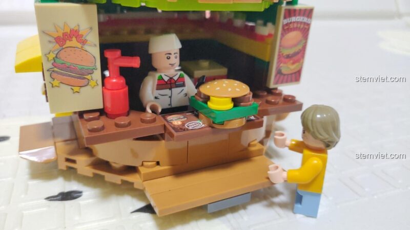 Chi tiết minifigure đầu bếp và khách hàng trong đồ chơi mô hình Sembo 601055. Người đầu bếp đang phục vụ một chiếc hamburger.