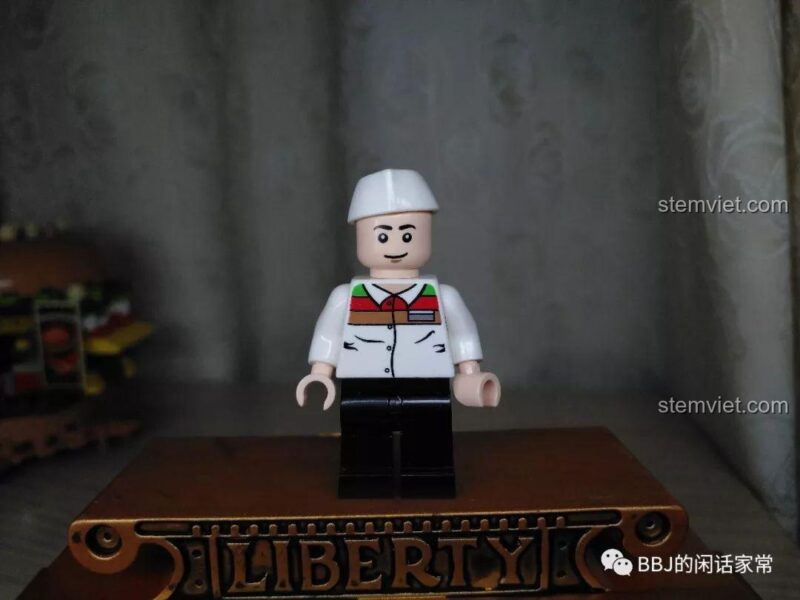 Cận cảnh minifigure đầu bếp trong bộ Tiệm bánh Hamburger Sembo, mặc áo trắng và đội mũ trắng.