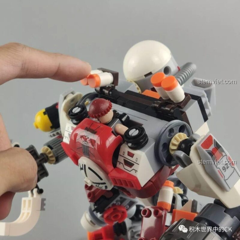 Minifigure ngồi trong buồng lái của mô hình Robot Chiến Đấu Kẻ Cướp Bóc Winner 5100, chỉ lộ mũ.
