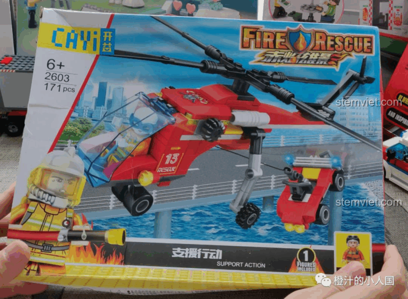 Người dùng cầm trên tay hộp đồ chơi lắp ghép Trực thăng cứu hộ CAYI 2603, cho thấy kích thước thực tế của sản phẩm.