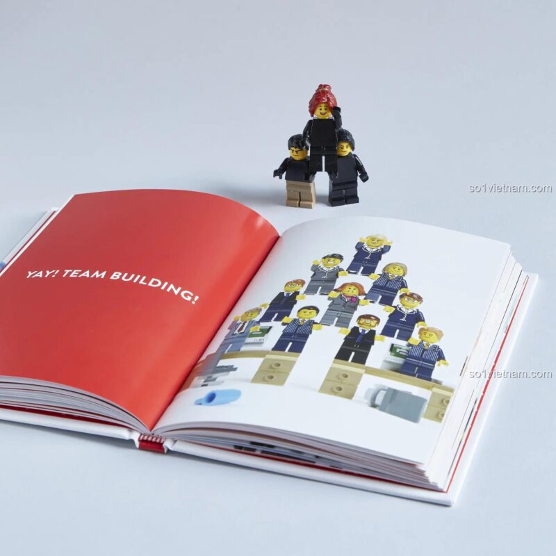 Sách truyện tình yêu LEGO® 1452182315 Sách về minifigures LEGO® 82315, trang sách mở với các minifigure xếp hình kim tự tháp, kèm câu nói YAY! TEAM BUILDING!, phù hợp cho thanh niên 12 tuổi, giá tốt.