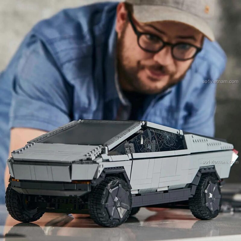 Người đàn ông đang lắp ráp mô hình Tesla Cybertruck Mega Bloks GWW84, thể hiện sự tập trung và hứng thú