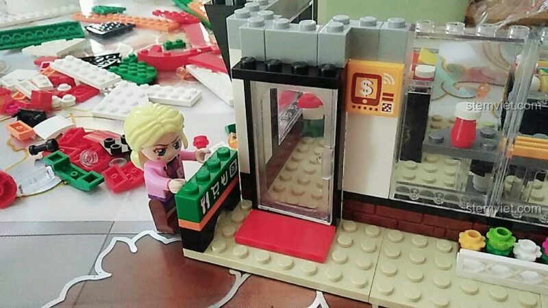 Ảnh review mô hình Cửa Hàng Tiện Lợi QMAN 1133 đã hoàn thiện với các minifigures khách hàng và nhân viên giao hàng.