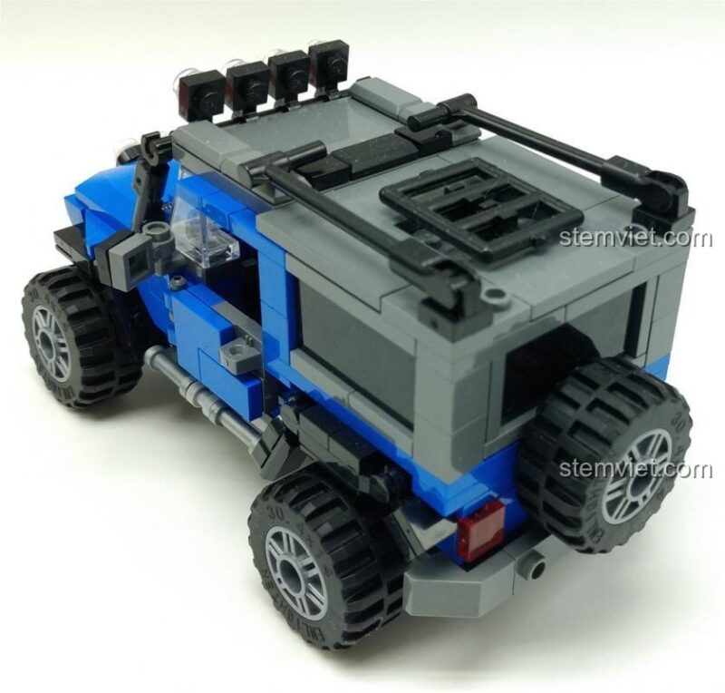 Mô hình Khủng long Robot QMAN, Xe Off-road ENLIGHTEN. Phần đuôi của mô hình xe SUV địa hình màu xanh dương, với bánh xe dự phòng và đèn hậu, cho thấy sự chú ý đến từng chi tiết của bộ đồ chơi lắp ráp ENLIGHTEN.