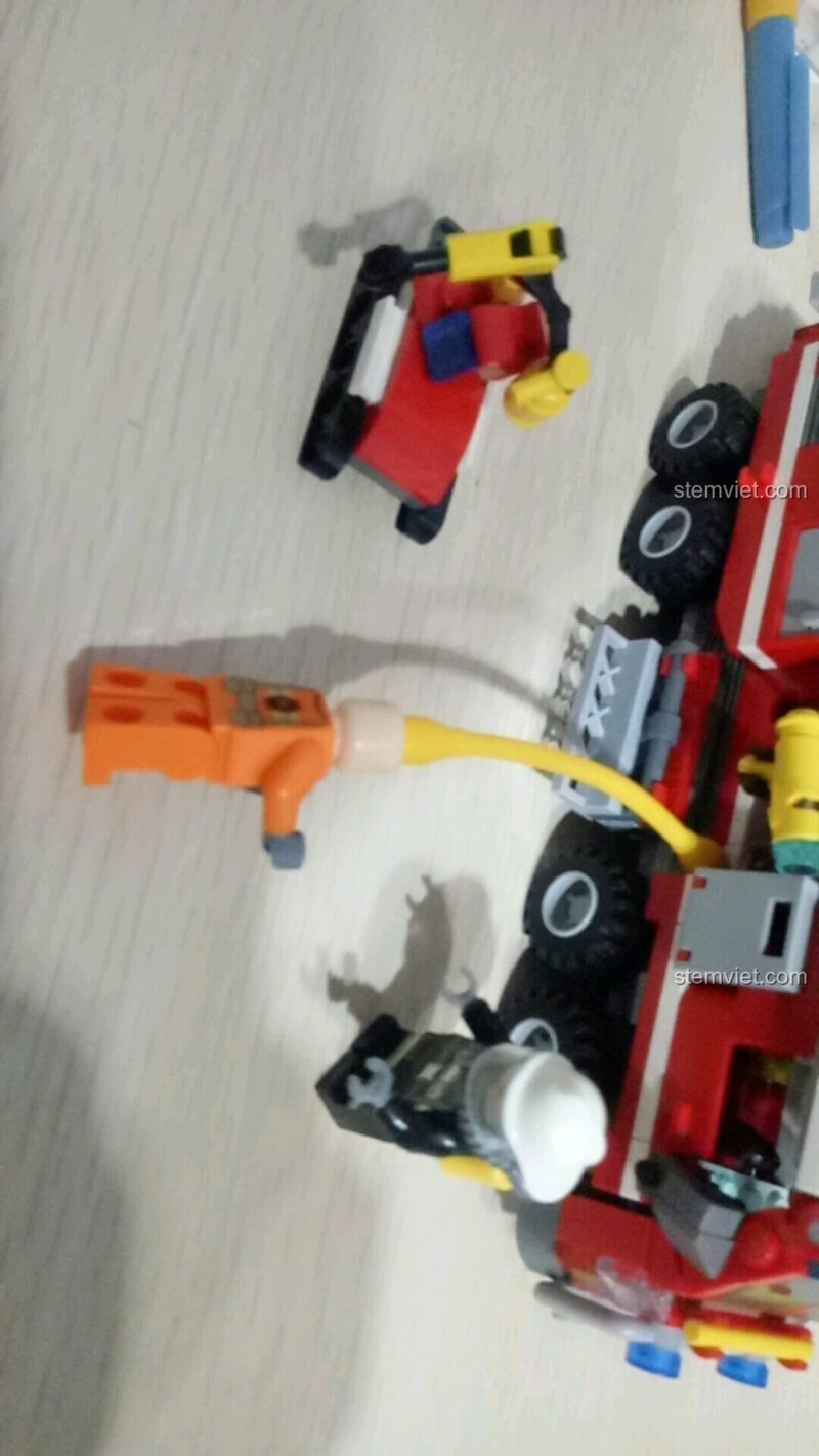 Minifigure lính cứu hỏa trong bộ đồ chơi SEMBO 603034 đang tương tác với vòi nước, tạo nên kịch bản chơi sáng tạo