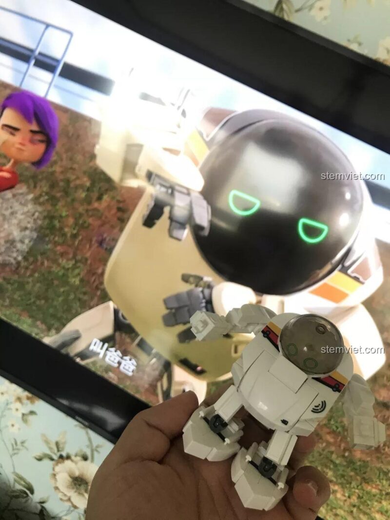 Bé trai 6 tuổi cầm đồ chơi mô hình Sluban B0761E Robot Q-Bricks Q-Phiên Bản, thể hiện kích thước nhỏ gọn, dễ chơi.