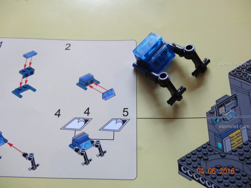 Robot mini được đặt trên đế của đồ chơi mô hình SY368 Trụ sở Siêu anh hùng, sẵn sàng cho nhiệm vụ.