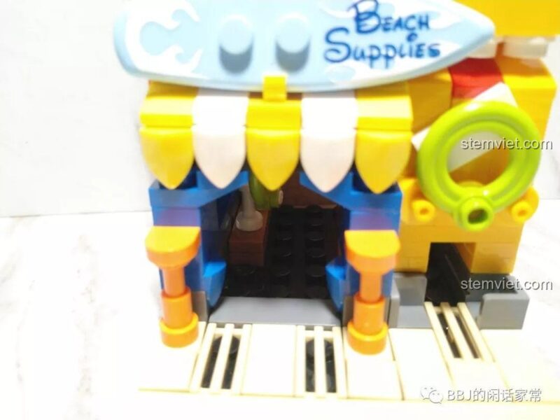 Cận cảnh chi tiết biển hiệu ván lướt sóng 'Beach Supplies' và mái hiên của đồ chơi mô hình SY6800A.