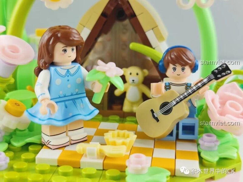 Ảnh chụp cận cảnh 2 minifigures trong bộ lắp ghép Wekki 516152, bé gái mặc váy xanh và bé trai đeo tai nghe, cầm đàn guitar.