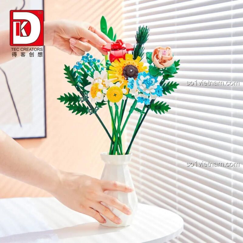 Bàn tay đang hoàn thiện bó hoa lắp ghép DK 3027, đặt vào lọ hoa trắng, thể hiện sự khéo léo và sáng tạo, đồ chơi giáo dục cho bé gái 8 tuổi