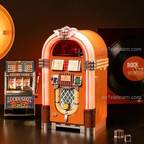 Mô hình máy phát nhạc retro Pantasy 85020 hoàn thiện, đặt trong bối cảnh cổ điển với máy chơi game slot và đĩa than. Mô hình có màu cam và nâu, chi tiết tinh xảo.